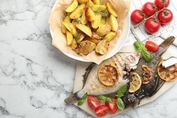 Homemade seafood dish. Tasty roasted flounder fish served with potatoes, tomatoes, basil and lemon slices on white marble table, flat lay. Space for text