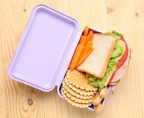 Open lunch box with tasty food on wooden table, top view