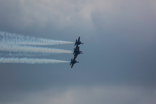 4 US Navy F/A-18  Super Hornet fighter attack jets flying in formation with streaking white trails