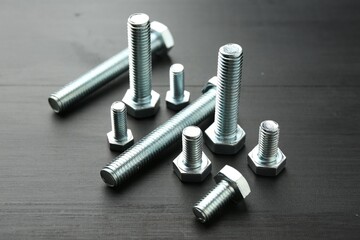 Metal bolts on dark wooden table, closeup