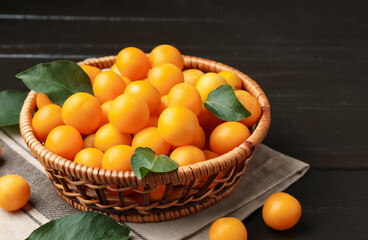 Ripe yellow cherry plums and leaves on dark wooden table, closeup