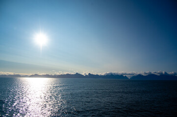 The sun reflects in the fjord near the Lofoten Islands in Norway in summer