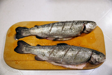 Raw trout lies on a cutting board for baking in the oven. Fish dinner recipes