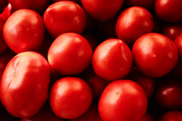 Fresh red tomatoes piled together at a local market. Close-up view of ripe organic vegetables, perfect for cooking, salads, or healthy eating concepts