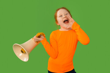 Child enthusiastically shouting into a megaphone while wearing a vibrant orange shirt against a...