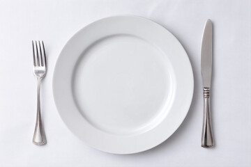 A round white plate is arranged neatly on a table with a fork and knife positioned beside it, ready for a meal in a western restaurant