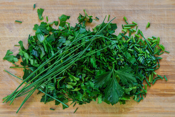 Fresh parsley and chopped chives on wooden cutting board for cooking