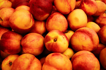 Fresh ripe nectarines piled together at the local market. Organic juicy fruit used for desserts, jams, and healthy snacks
