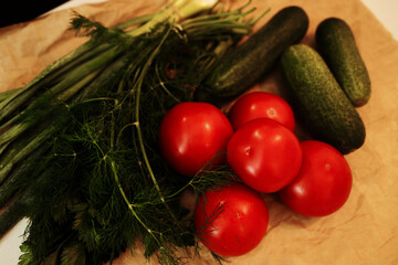 Fresh tomatoes, cucumbers, dill, and green onions on paper. Organic vegetables from local market