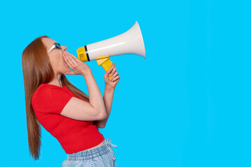 Woman yelling through a megaphone on a blue background, expressing enthusiasm and energy during an...