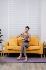 Obraz premium Woman Eating Salad on Sofa After Workout