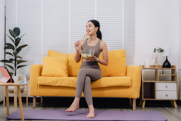 Fototapeta premium Woman Eating Salad After Online Yoga Class