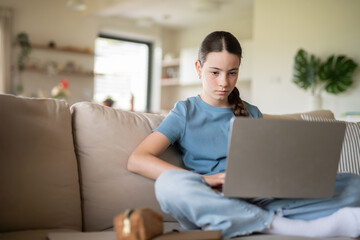 Teenage girl struggling with school project, working on laptop.