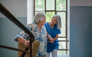 Female healthcare worker helping senior patient walking up the stairs.