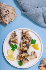 Pickled rapan meat with oil, spices and greens. Healthy seafood rich of omega