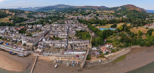 Fototapeta premium Aerial view of Conwy, Wales, showing the historic town walls, waterfront, and surrounding countryside summer skies.