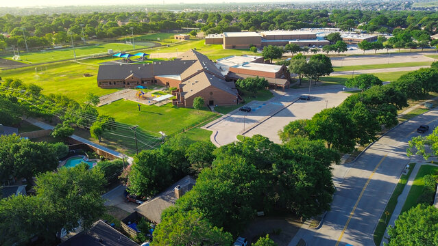 Aerial view of Coppell ISD top-ranked school campus, showing dual elementary and middle school buildings, playgrounds, and sports fields surrounded by upscale suburban homes and greenery, Texas