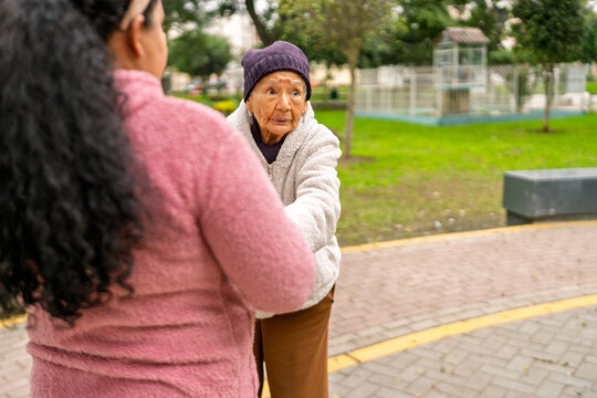 Nurse assisting elderly woman walking in park - Powered by Adobe