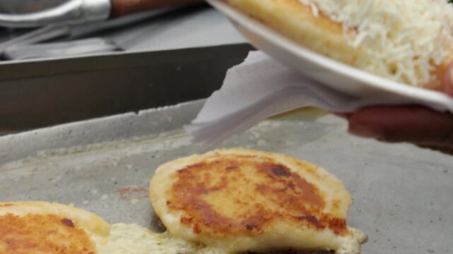 Delicious Arepa with Grated Cheese Being Prepared on a Griddle