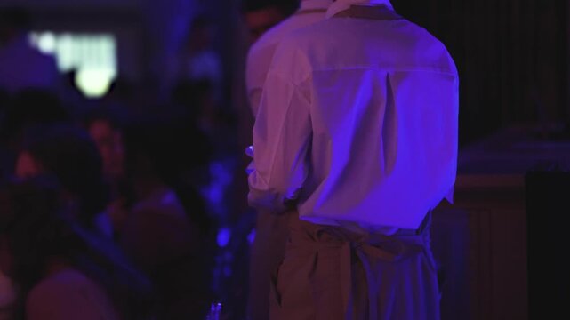 Waiter in uniform serving dishes and drinks on party event dinner, server carrying plates with food and beverages at the table, catering service on wedding reception, table service in cafe restaurant