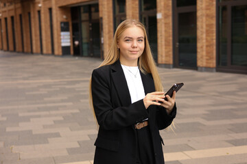 Businesswoman in formal attire using smartphone, replying to messages.