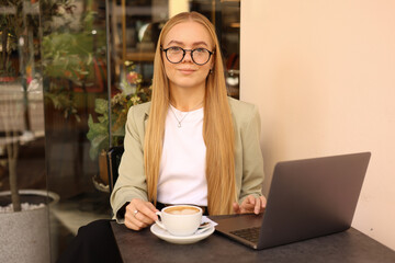 Smiling freelancer with coffee cup sitting in cafe