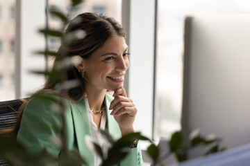 Close up professional Latina businesswoman sit at desk, smiling thoughtfully, looks at computer...