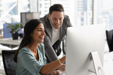 Cheerful female employee engaged in positive collaborative conversation with male colleague,...