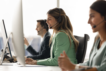Group of customer service representatives sit at modern office workstation, focus on young Hispanic...