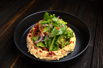 Hummus with Roasted Vegetable Salad and Fresh Greens on Dark Wooden Background