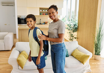 Mother helping son to get ready for school, helping him with backpack and books, hugging and...