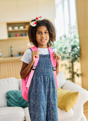Portrait of a young black teenage girl ready for school, preparing and packing her backpack at home