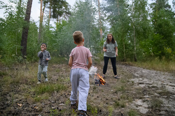 Family Roasting Marshmallows Over Campfire in Forest