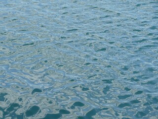 Sunlit water surface softly undulating, reflecting serene natural lighting and calm environment
