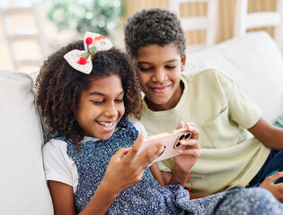 Portreit of brother and sister having fun using a smartphone mogile phone playing a game or brwsing...
