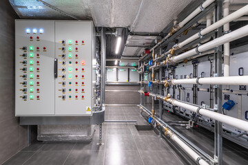 Advanced control systems are displayed on a wall with various indicators, while extensive piping...
