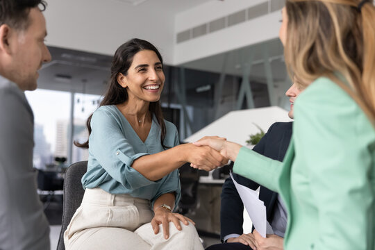 Smiling Brazilian female professional seals successful business interaction with confident handshake during formal meeting with woman colleague or business partner. Leadership, teamwork, collaboration