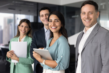 Confident diverse business team standing together in modern office, look at camera with joyful,...