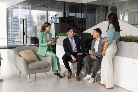 Teammates of creative marketing department gathered in office, discussing new product or services launch, exchanging ideas or solutions, listening mature team leader express point of view. Teamwork