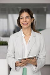 Happy businesswoman in formal attire hold digital tablet looks into distance with contented smile,...