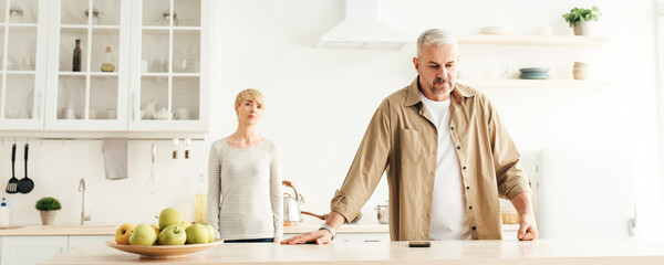 Problems at home, aggression and domestic violence. Upset middle aged husband and wife quarrel in...
