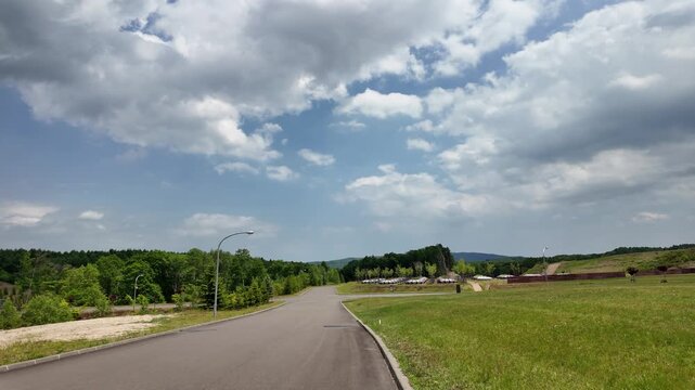 A peaceful country road stretches through vibrant greenery and under a clear blue sky. The scene captures the essence of tranquility and natural beauty, perfect for nature lovers and those seeking esc