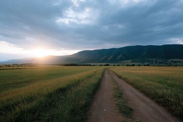 Fototapeta premium Sunset over serene rolling hills and dirt path in vast countryside landscape