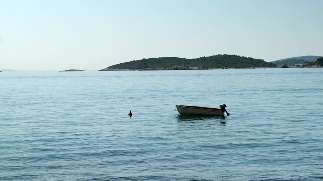 A small boat is floating in the ocean with a buoy attached to it