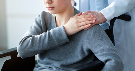 Handicapped teenage boy in wheelchair feeling depressed, nurse taking care of him at home, copy...
