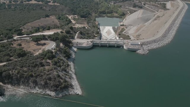 Bradbury Dam at Cachuma Lake, California is shown from an aerial, approaching view in real time during a summer day. This dam spans the Santa Ynez River and was constructed in the 1950s.