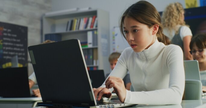 Primary School Girl Working on Creative Project on Laptop, Practicing Digital Skills in Art Class. Young Kids Drawing, Doing Tasks on Digital Devices in Modern Classroom. Interactive STEM Learning.