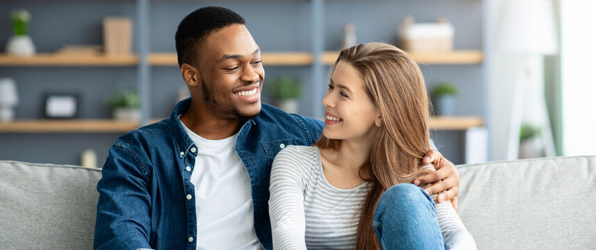 Portrait Of Loving Interracial Couple Relaxing Together At Home, Romantic Multicultiral Lovers Hugging On Couch In Living Room, Smiling Black Man And White Woman Enjoying Spending Time With Each Other