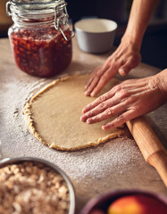Rolling Out Dough by Hand on Floured Surface in Cozy Kitchen