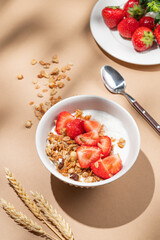 Granola or muesli with natural greek yogurt and strawberry in a bowl on a beige background